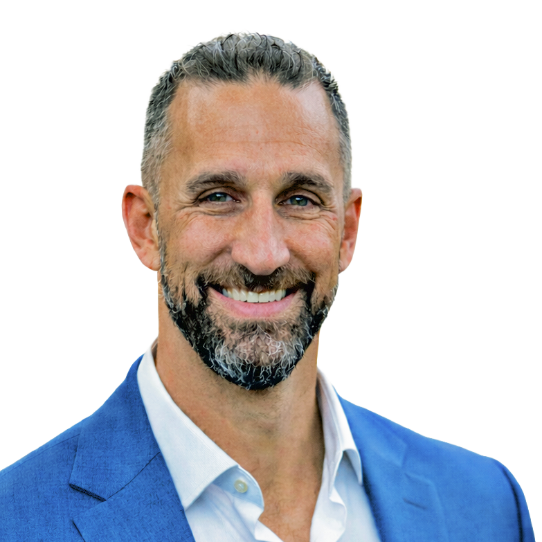 Smiling man with a salt-and-pepper beard wearing a blue suit jacket and white shirt, standing against a plain white background.