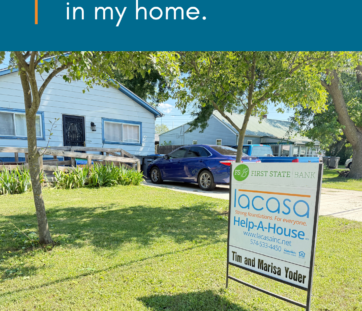 Blue house with a ramp, a car in the driveway, and a yard sign for Help-A-House, featuring a quote about feeling safe at home.