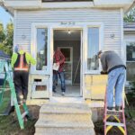 People working on a lacasa home project in Goshen, Elkhart, fixing up the front porch and making improvements together on a sunny day.